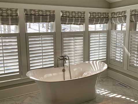 A bathtub in a room with walls covered in windows and shutters