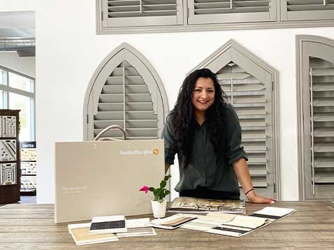 A woman leaning over a desk covered by Hunter Douglas samples