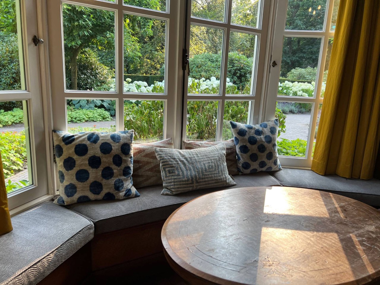 A bay window seat with cushions, drapes, and a table at Appalachian Blind & Closet Co. near Boone, NC