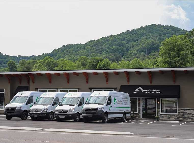 The storefront with a line of company vehicles backed by a lush mountain